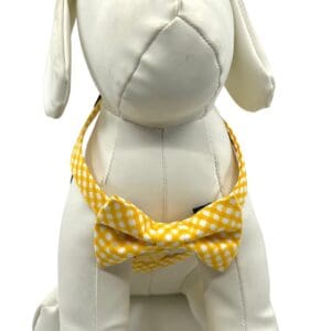 A white dog wearing the Yellow Gold Check- "H" Style Harness w/Bow Tie.