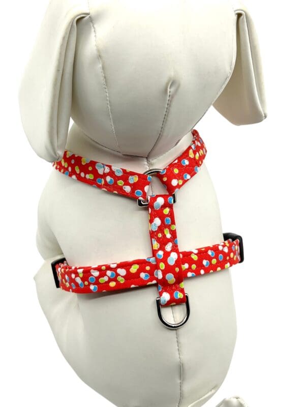 A dog wearing a red polka dot harness.