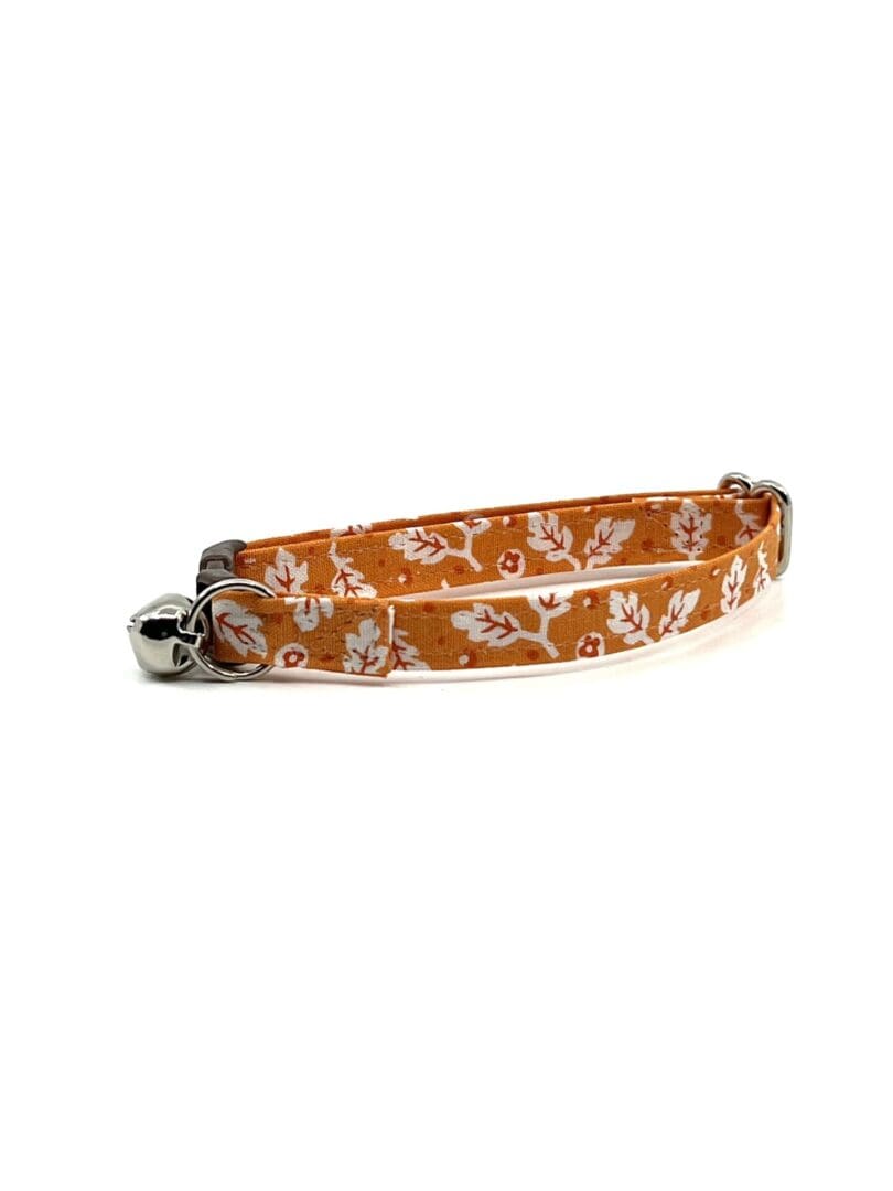 A cat collar with an orange and white floral pattern.