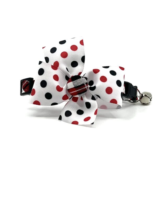 A white and black polka dot bow with red and black stripes.