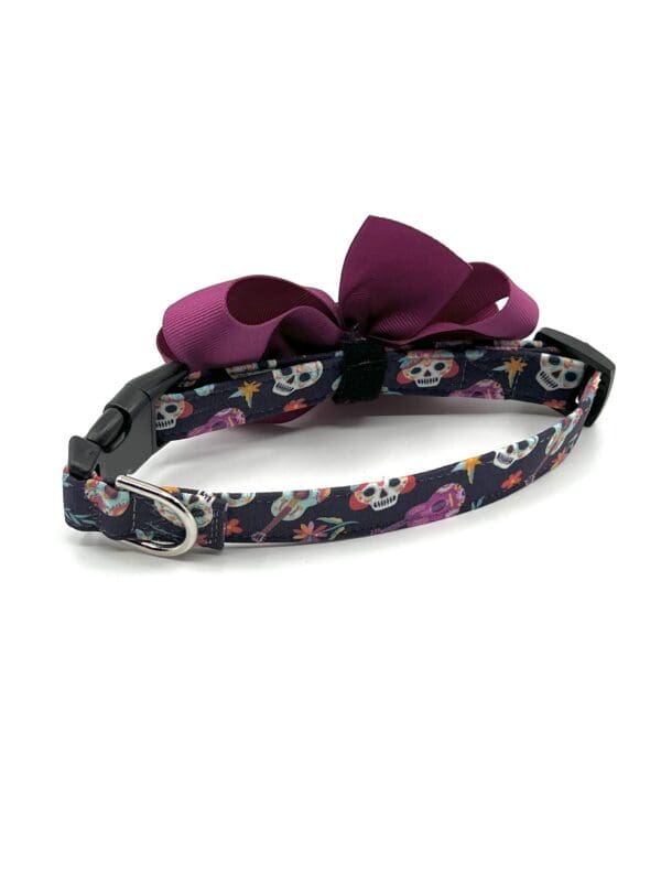A dog collar with skulls and bows on it.