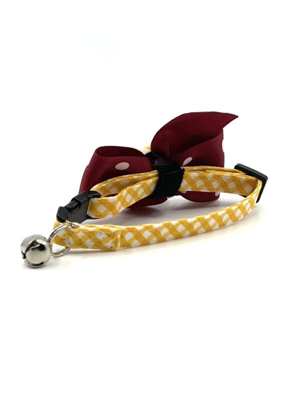 A yellow and maroon cat collar with a bow.
