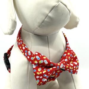 A dog wearing a red polka dot bow tie.