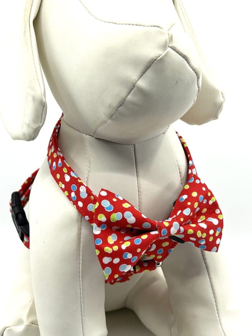 A dog wearing a red polka dot bow tie.