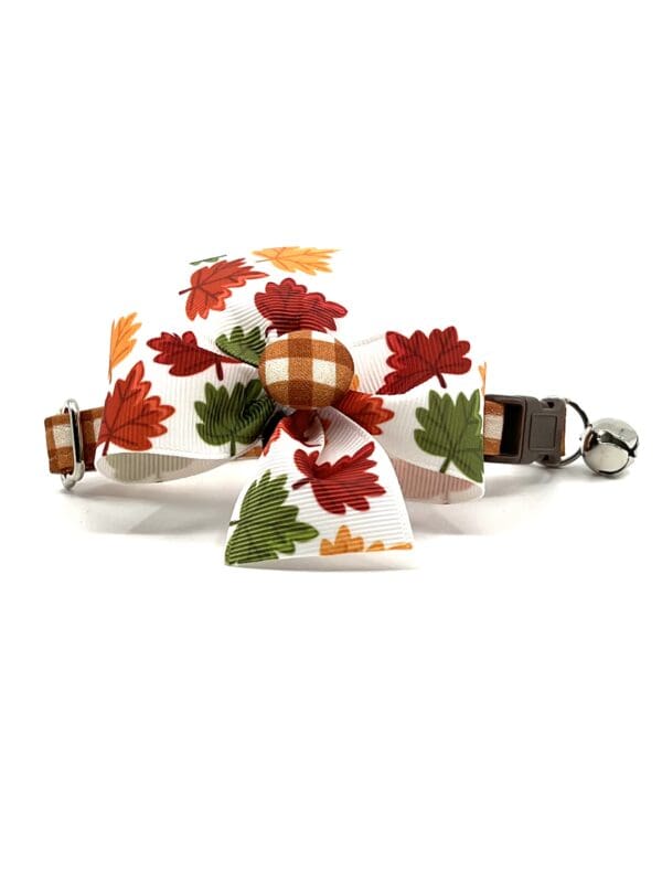 A cat collar with a plaid bow and leaves.