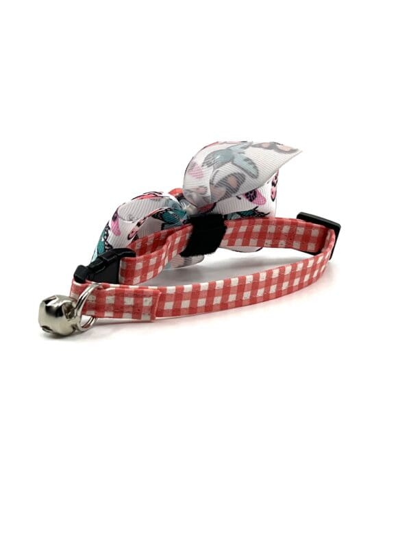 A red and white gingham cat collar with a bow.