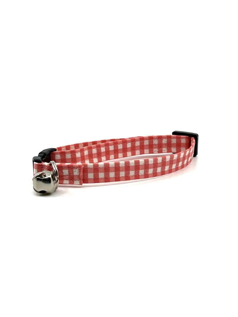 A red and white gingham cat collar with a bell.