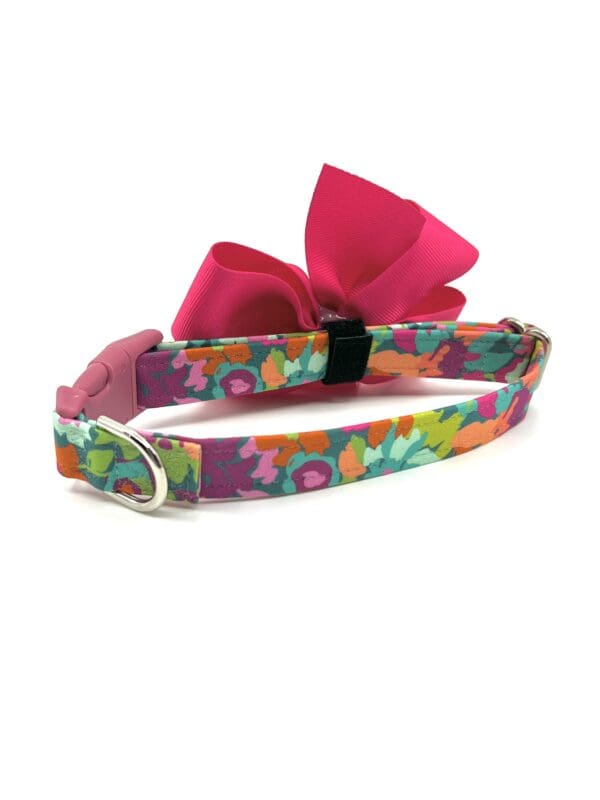 A pink bow on a colorful floral print dog collar.