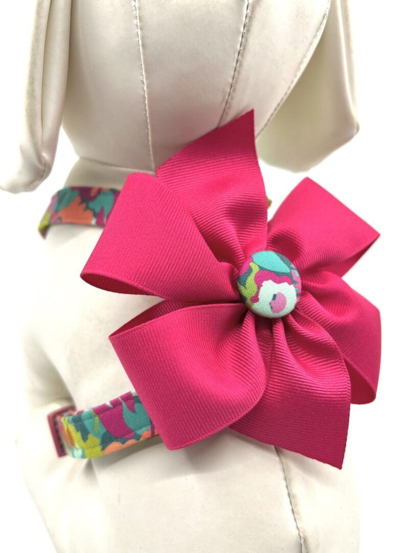A pink bow is on the end of a dog collar.