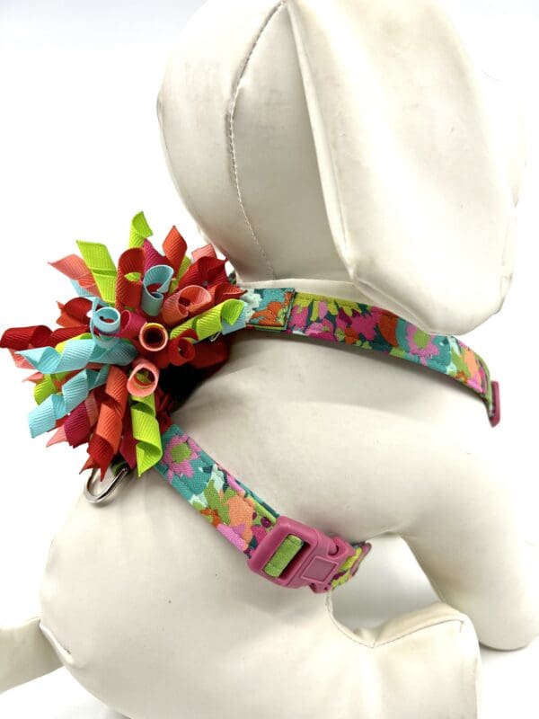 A dog wearing a colorful harness with flowers on it.