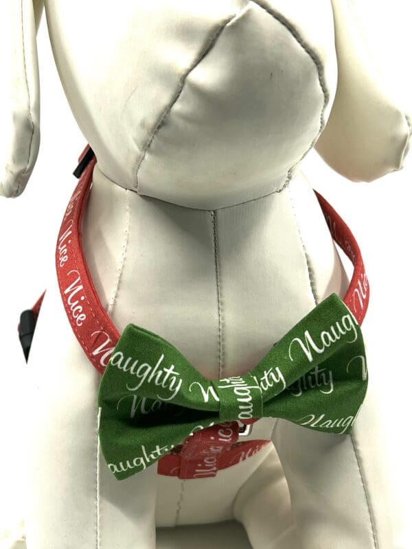 A dog wearing a bow tie with the words " naughty but nice ".