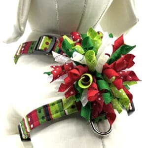 A dog harness with red, green, and white ribbons.