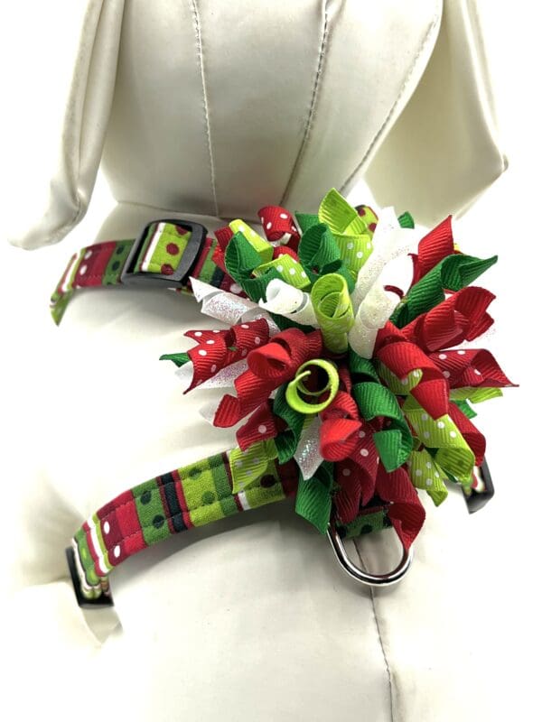 A dog harness with red, green, and white ribbons.