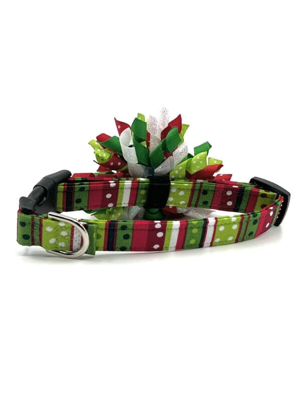 A green, red and white dog collar with a bow.