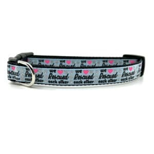 A gray dog collar with pink hearts on it.