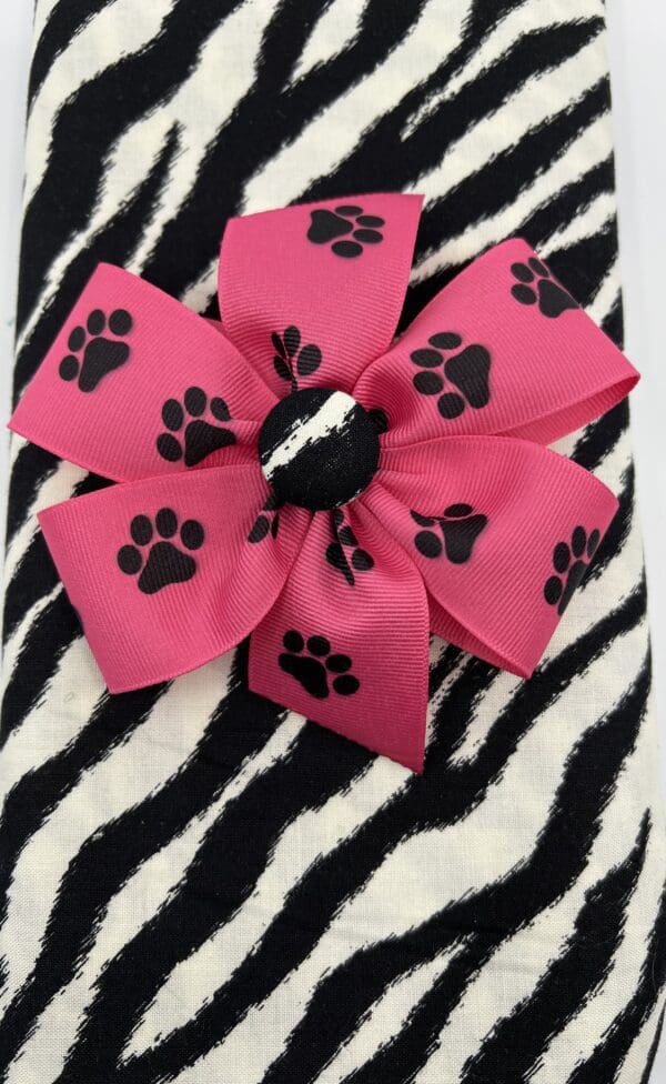 A pink bow with black paw prints on it.