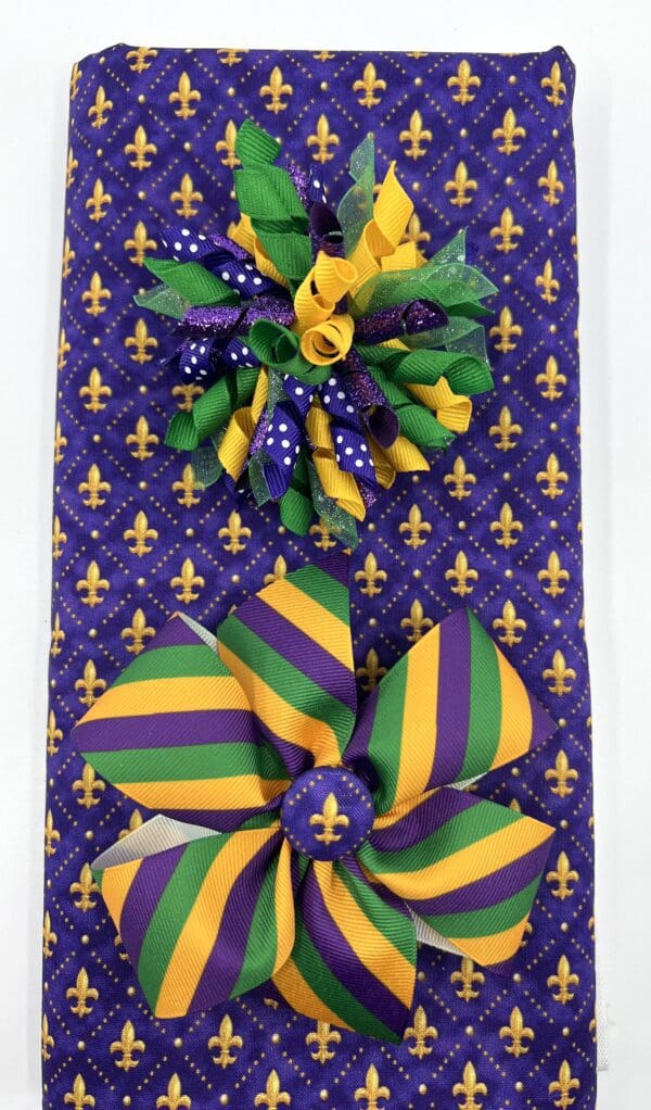 A purple, green and yellow bow on top of a gift bag.