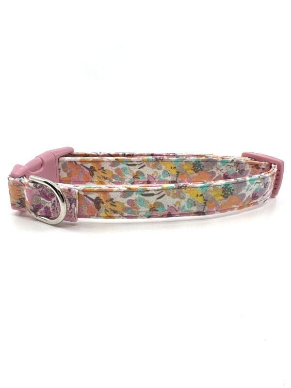 A pink and white floral dog collar with a pink peace sign on it.