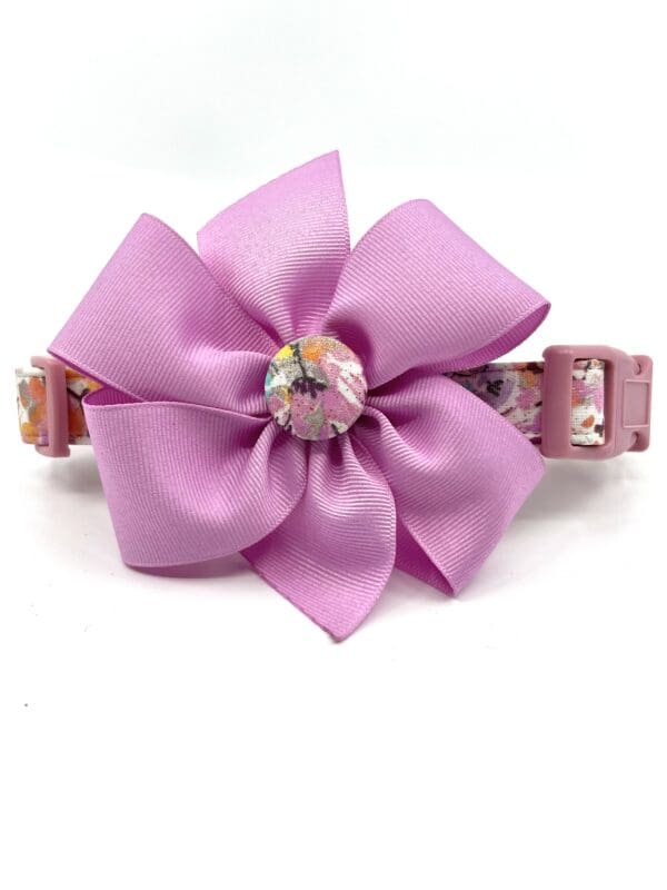 A pink dog collar with a flower on it.
