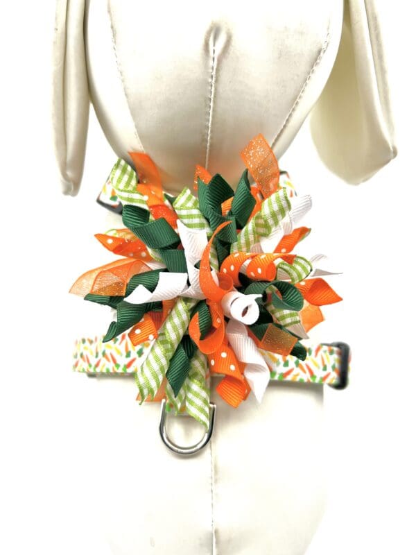 A dog harness with orange and green ribbons.