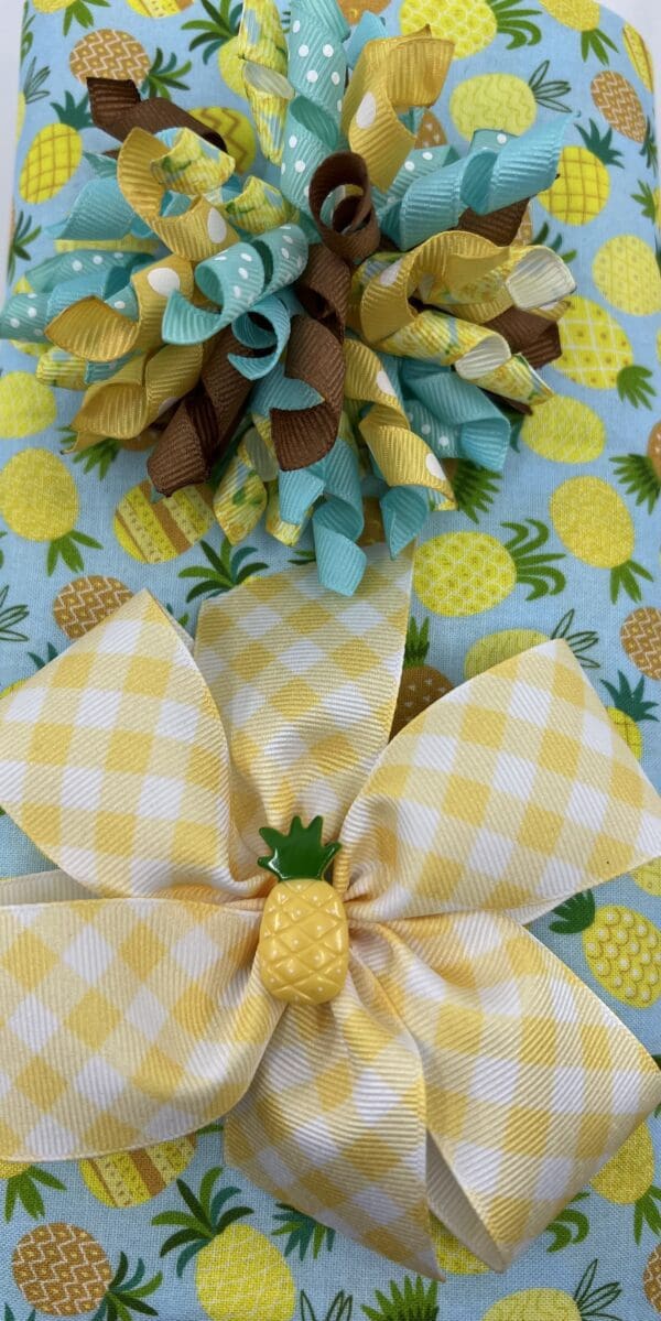 A gift wrap with pineapples and bows on it.