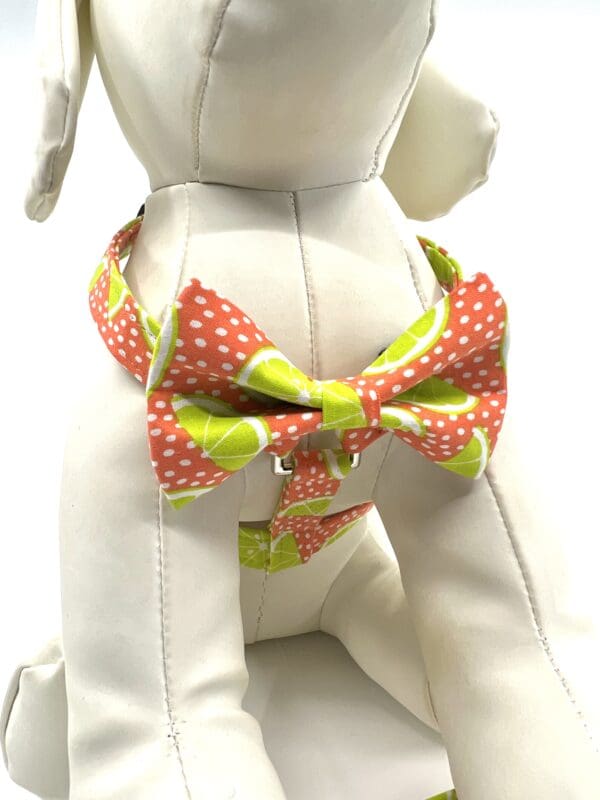 A white dog wearing a bow tie with green and pink polka dots.