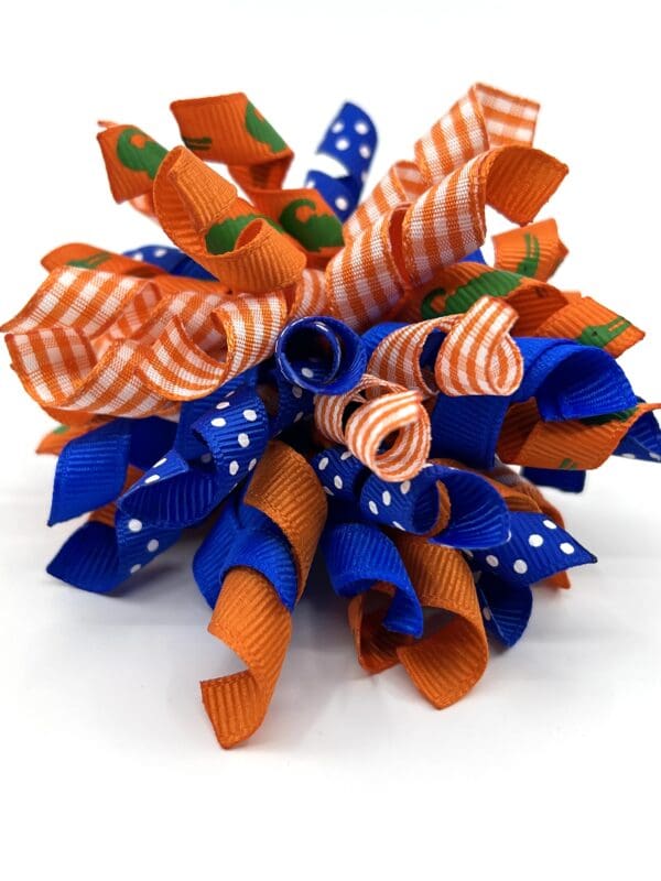 A blue and orange ribbon flower with green leaves.