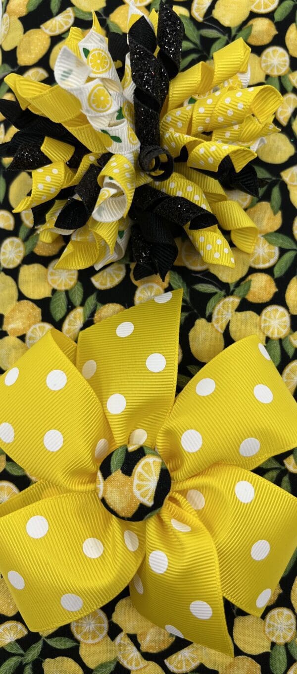 A black and yellow polka dot bow with lemons on it.