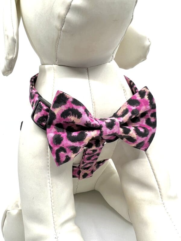 A dog wearing a pink leopard print bow tie.
