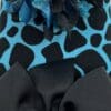 A close up of the bow on a blue and black animal print shoe.