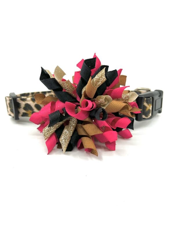 A leopard print dog collar with a pink and black flower.