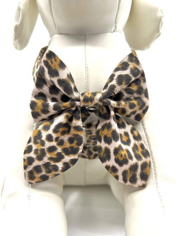 A leopard print bow tie sitting on top of a white chair.