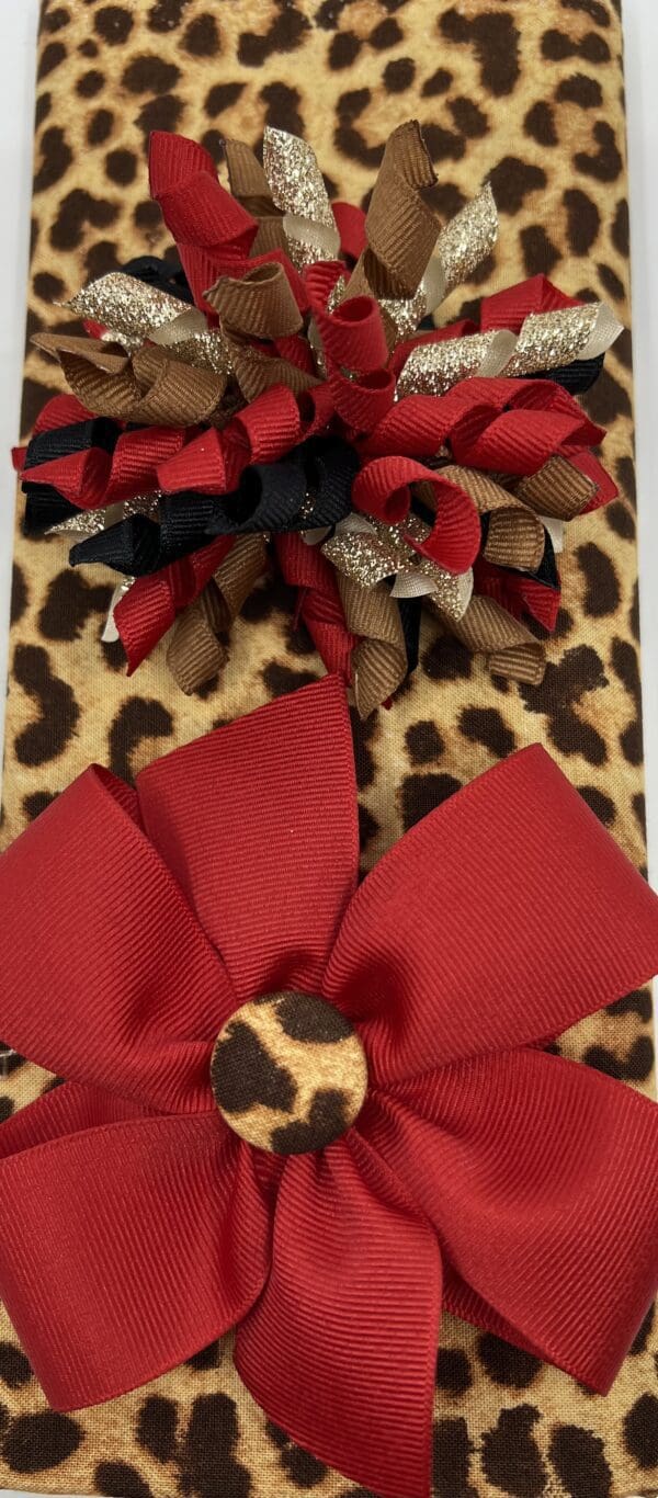 A leopard print purse with red and black bows.
