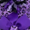 A purple bow on top of a leopard print bag.