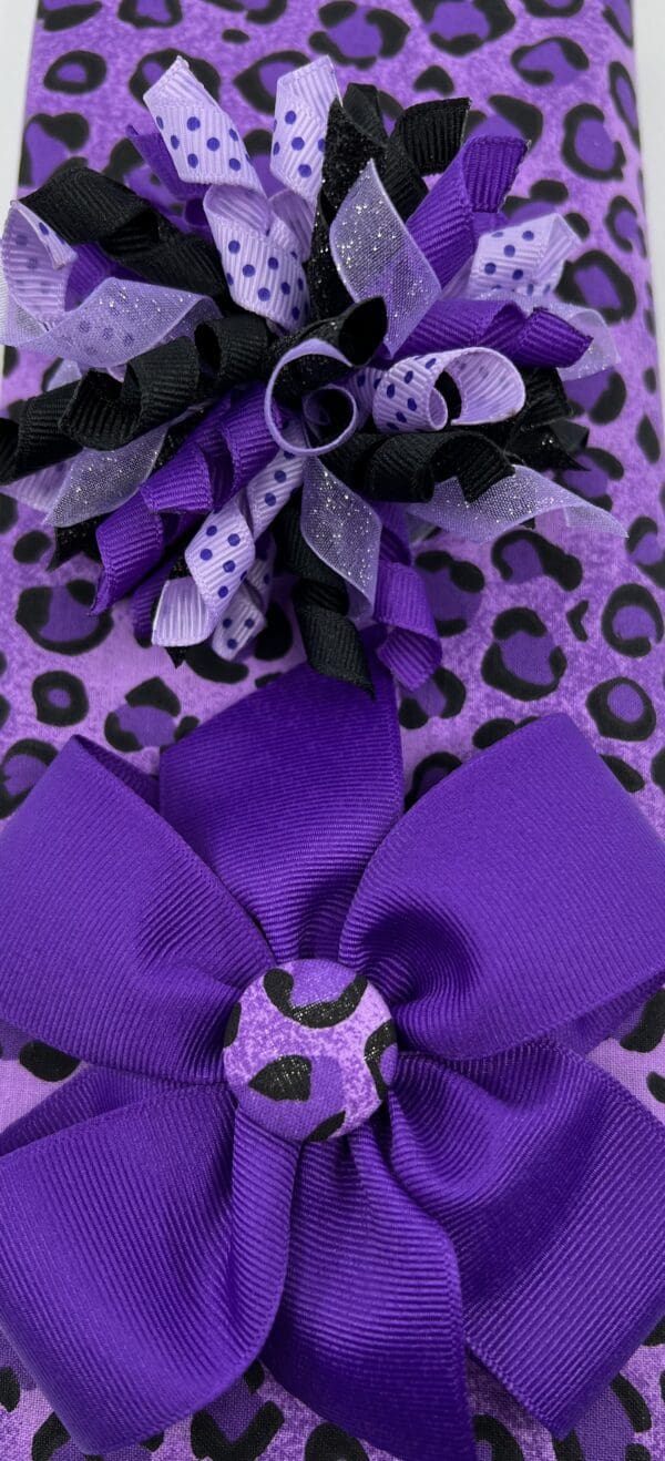 A purple bow on top of a leopard print bag.