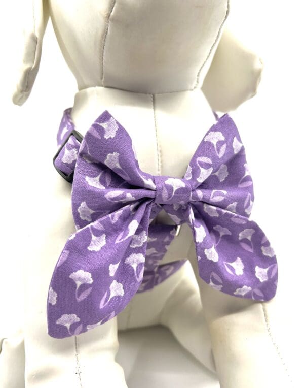 A purple bow tie with white cats on it.