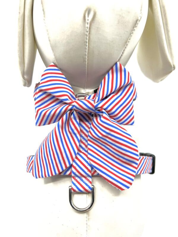 A dog harness with a red, white and blue bow.