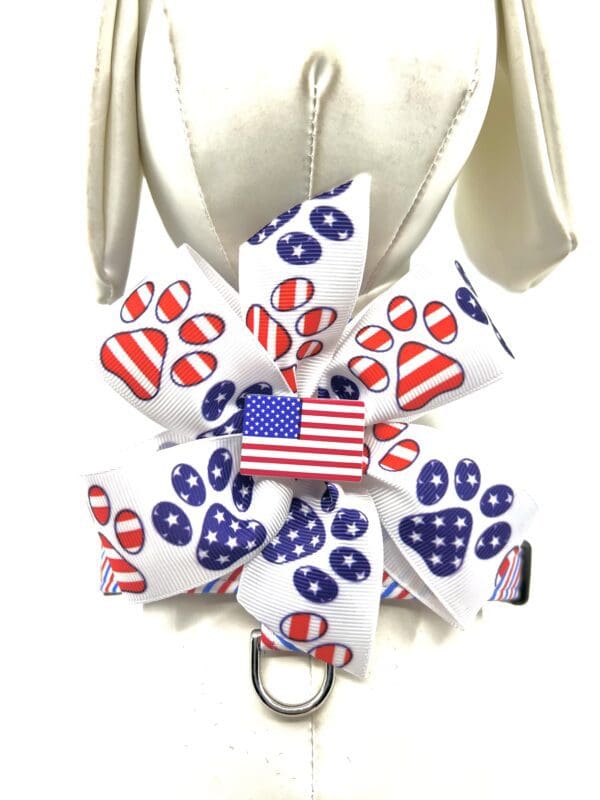 A dog 's harness with a bow and paw prints.