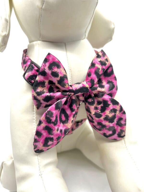 A dog wearing a pink leopard print bow tie.