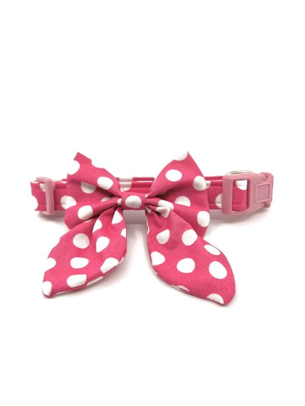 A pink bow tie with white polka dots on it.