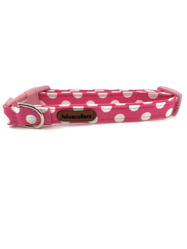A pink polka dot dog collar with a metal buckle.