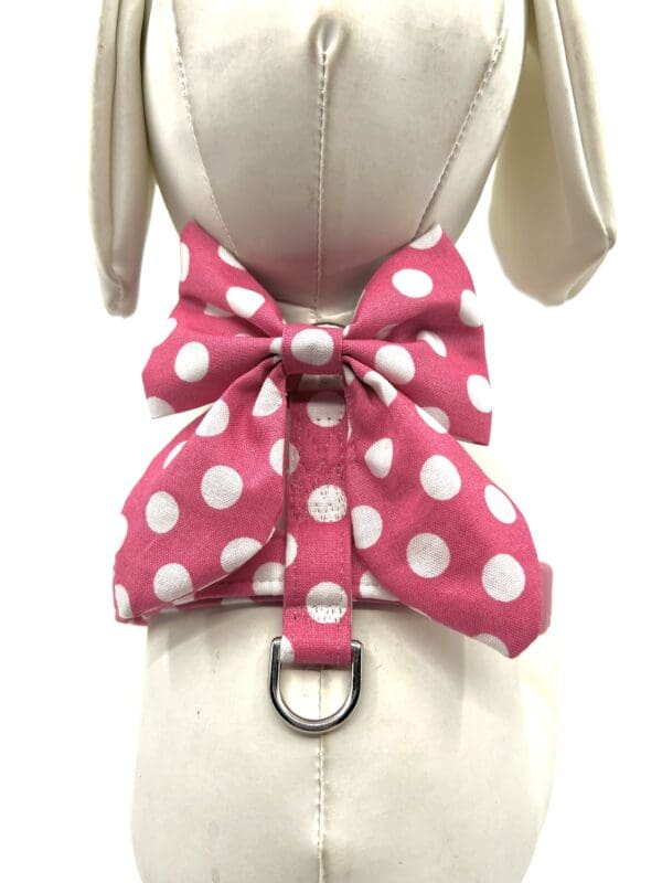 A pink polka dot bow tie on top of a white dog collar.