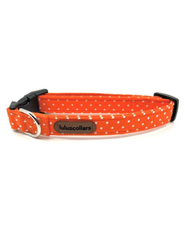 A dog collar with an orange polka dot pattern.