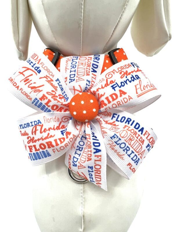 A white collar with a bow and orange polka dot button.