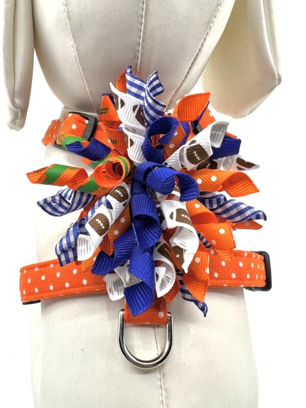 A dog 's harness with orange and blue ribbons.
