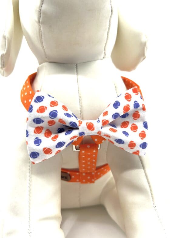 A white dog wearing an orange and blue bow tie.