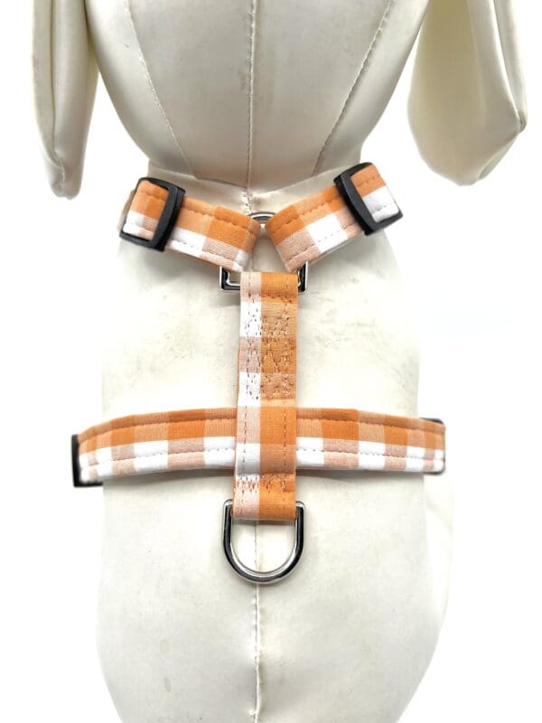 A dog harness with an orange and white plaid pattern.