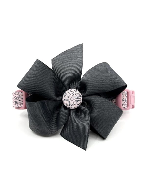 A black bow with pink ribbon and a diamond center.