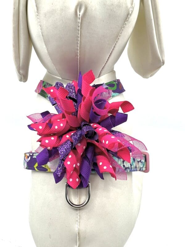 A dog 's harness with purple and pink flowers.