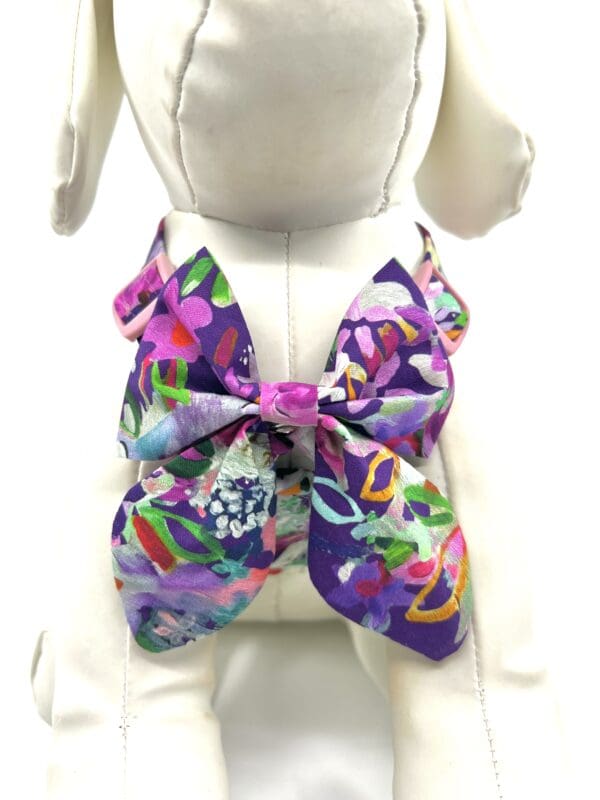 A purple bow tie with colorful flowers on it.